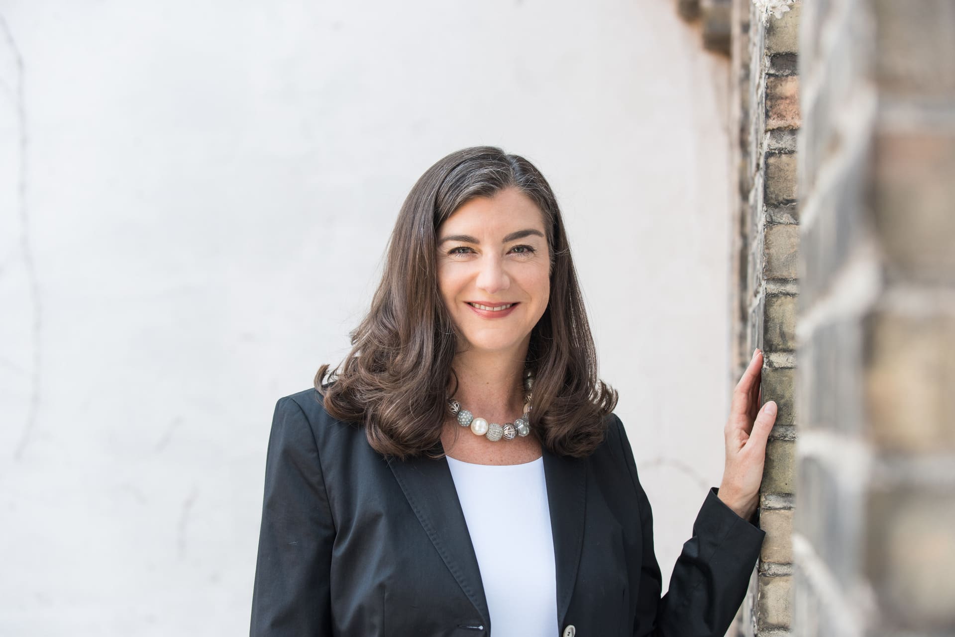 Susanne Schlenker lehnt an Wand mit Hand und schaut in die Kamera