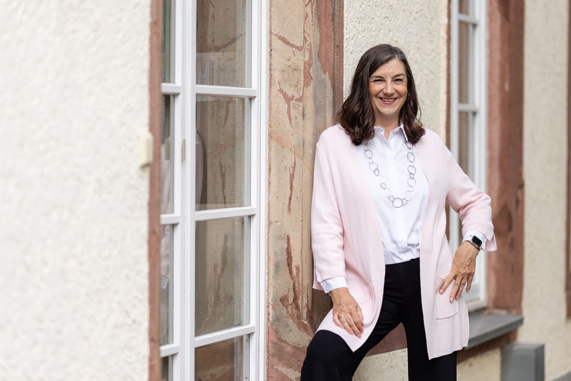 Frau lehnt an Hauswand